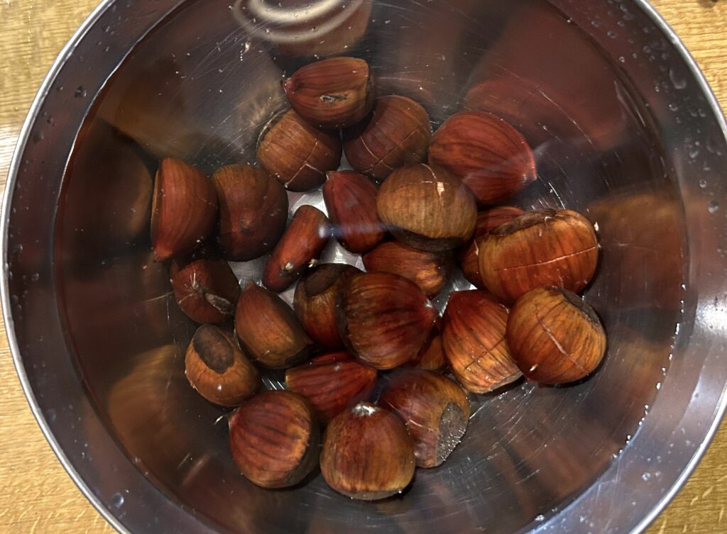 scored chestnuts in a bowl with warm water