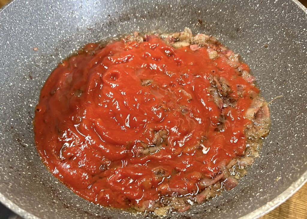 add the tomato puree above guanciale