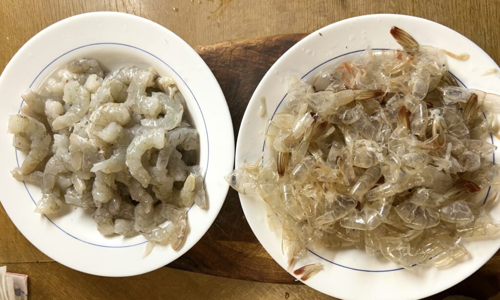 prawns on one plate and the shells and head on another plate