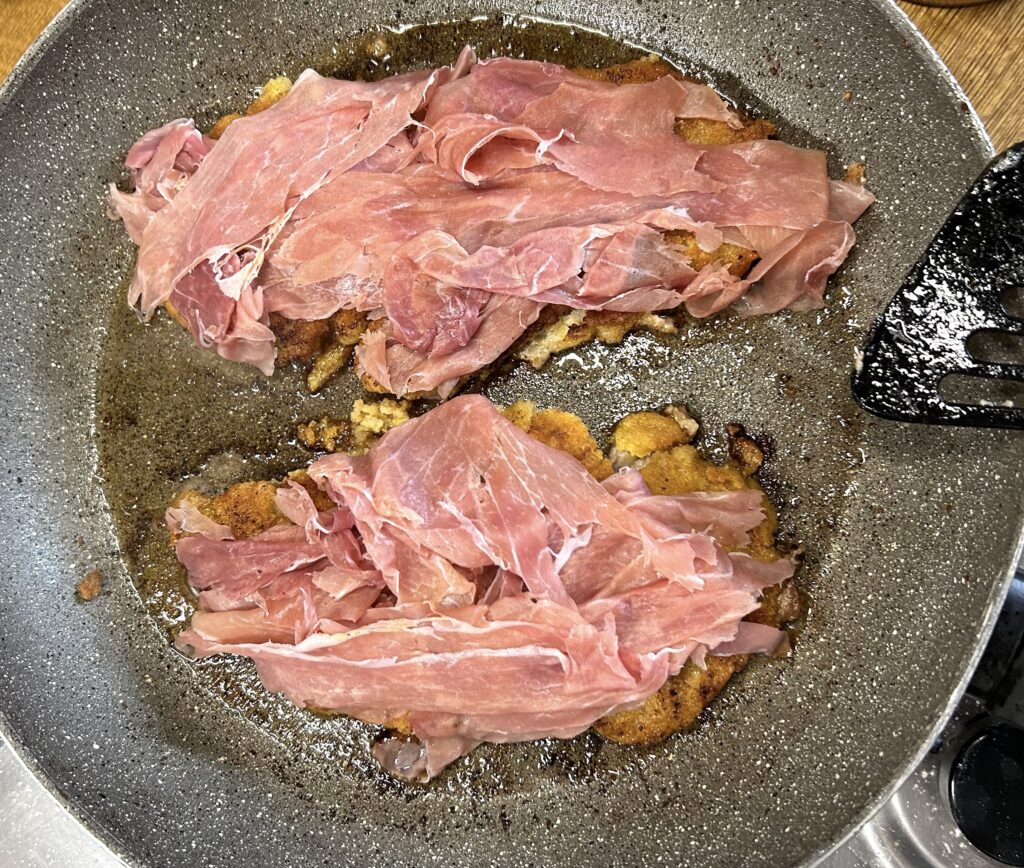 sliced ​​raw ham on top of cooked cutlets